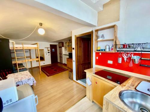 una cucina con lavandino e parete rossa di Monolocale accogliente a Bardonecchia