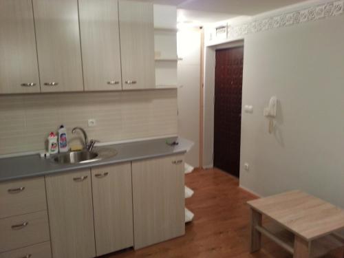 a kitchen with white cabinets and a sink and a table at Beautiful View Of Sarajevo Center in Sarajevo
