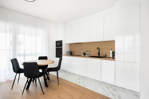 a kitchen with white cabinets and a table and chairs at Brzeziny Deluxe Apartment in Warsaw