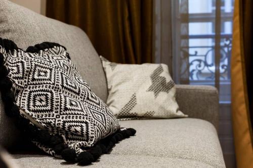a couch with two pillows on it with a window at Pur bonheur Hôtel de ville - clim et balnéo AIL in Lyon