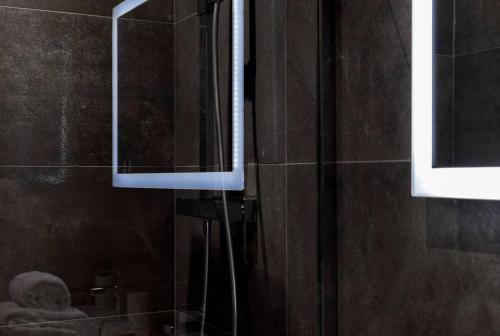 a bathroom with a shower with a mirror at Pur bonheur Hôtel de ville - clim et balnéo AIL in Lyon