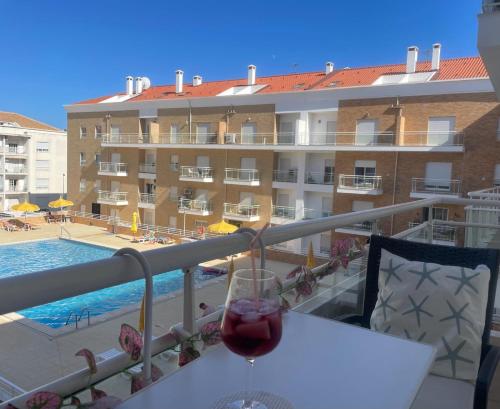a glass of wine sitting on a table on a balcony at Paradise Found - Stunning 3 Bedroom Apartment in Vila Real de Santo António in Vila Real de Santo António