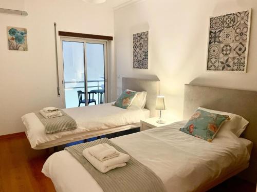 two beds in a room with a view of a balcony at Paradise Found - Stunning 3 Bedroom Apartment in Vila Real de Santo António in Vila Real de Santo António