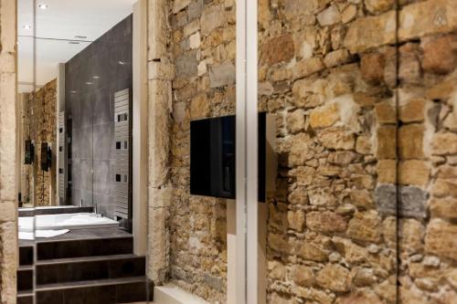 a stone wall in a bathroom with a television on it at 70m2 of pure happiness in the centre - Rhône in Lyon