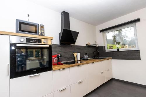 cocina con armarios blancos y microondas en Südschleife Apartments - App. 3 - Direkt am Ring, en Reimerath
