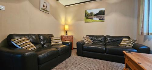 a living room with two leather couches and a table at Ash Cottage in Stranraer