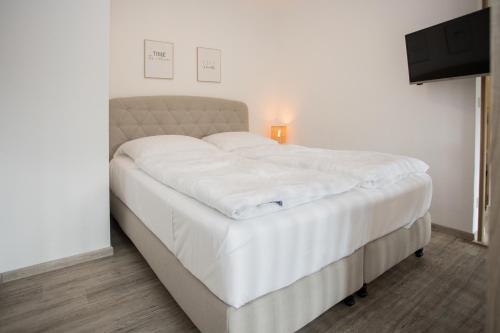 uma grande cama branca num quarto com televisão em Hackeschladenweg 15 - Winterberg 'Auszeit Winterberg' em Winterberg