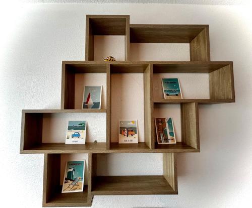 une étagère en bois sur un mur avec des photos dans l'établissement Studio MAJA proche des plages parking, à Saint-Nazaire