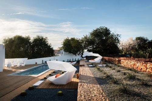 a garden with white chairs and a swimming pool at Boutique Hotel - Casa Esteval in Rocha Amarela