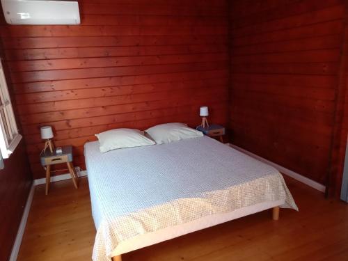 ein Schlafzimmer mit einem Bett in einer Holzwand in der Unterkunft Bungalow des papayes in Saint-Louis