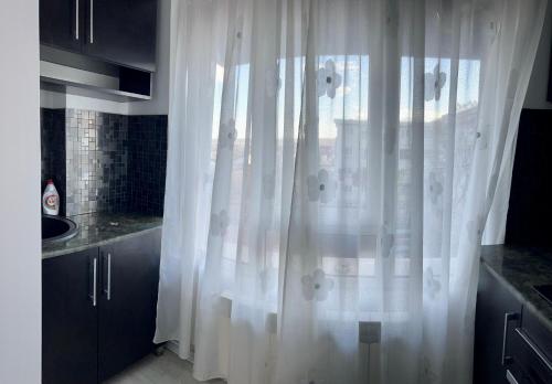 a white curtain in a kitchen with a sink at Lion House in Drobeta-Turnu Severin