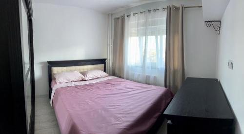a bedroom with a bed with pink sheets and a window at Lion House in Drobeta-Turnu Severin