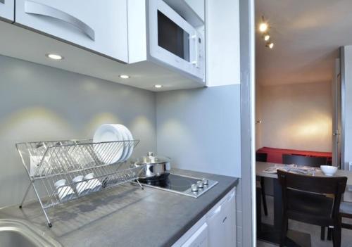 une cuisine avec des armoires blanches, un évier et une cuisinière dans l'établissement travelski home select - Résidence 3000, à La Plagne Tarentaise