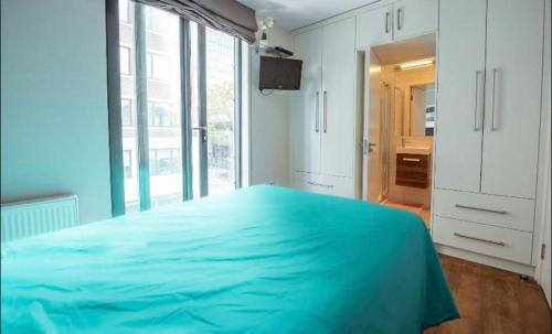 a bedroom with a blue bed and a large window at Splendid Euston flat in London