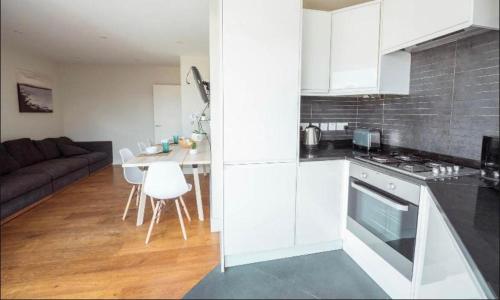 a kitchen with white cabinets and a table and a couch at Splendid Euston flat in London