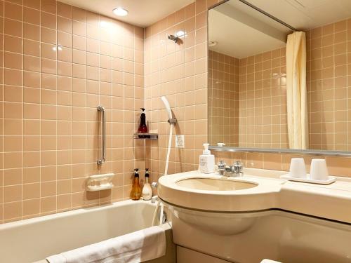 a bathroom with a sink and a toilet and a tub at Nakajimaya Grand Hotel in Shizuoka