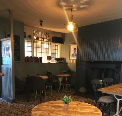 a restaurant with tables and chairs and a fireplace at The Victorian Tap in Hexham