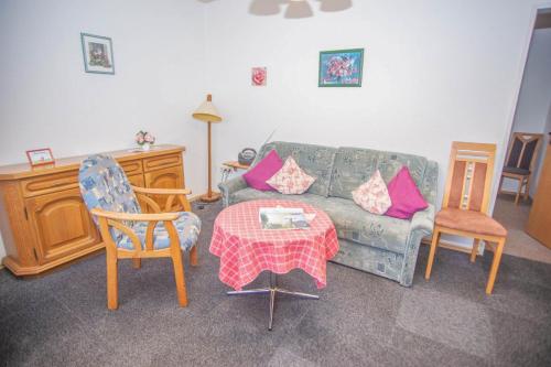 ein Wohnzimmer mit einem Sofa, einem Tisch und Stühlen in der Unterkunft Haus Ufen - In den Dünen 18c in Norderney