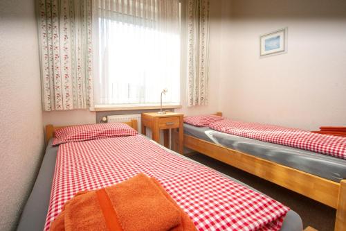 2 Einzelbetten in einem Zimmer mit Fenster in der Unterkunft Haus Ufen - In den Dünen 18c in Norderney