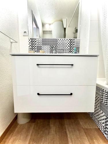 - une commode blanche dans la salle de bains pourvue d'un miroir dans l'établissement Studio MAJA proche des plages parking, à Saint-Nazaire