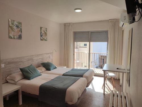 a hotel room with two beds and a balcony at Hostal Garamar in Benicàssim