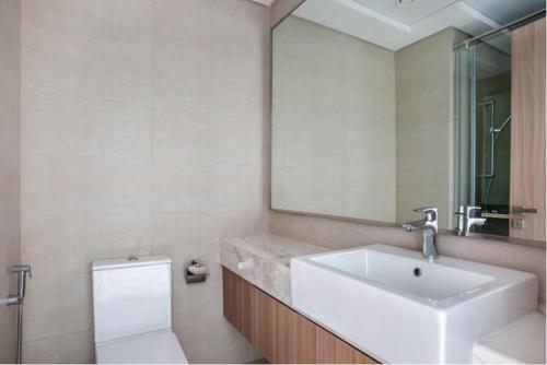 a bathroom with a sink and a toilet and a mirror at Azizi Riviera Small Family Private Apartment Dubai in Dubai