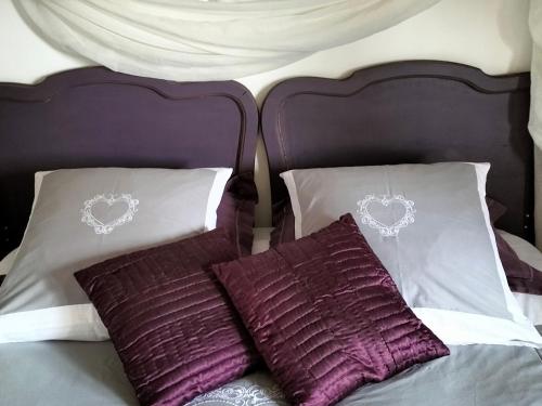 a bed with purple and white pillows on it at Chambres d'Hôtes Le Grismoustier in Veulettes-sur-Mer
