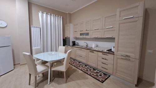 a kitchen with a table and white cabinets and a table and chairs at Casa Vacanze Enrica House in Naples