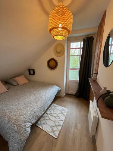 a bedroom with a bed and a chandelier at Au cœur des Remparts de Guérande: logement pour 4 in Guérande