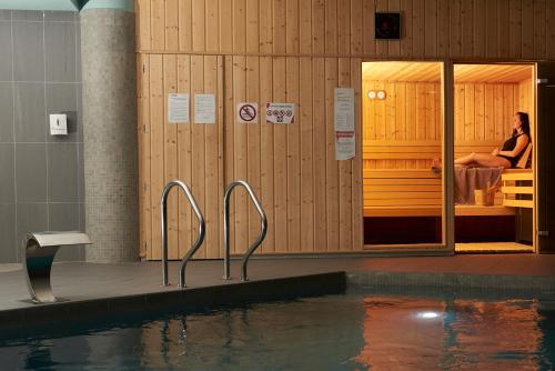 a swimming pool with a woman sitting on a bed at Villages Clubs du Soleil - OZ EN OISANS in Oz