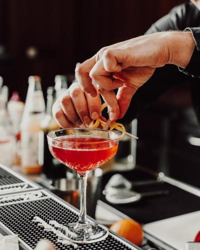 a person preparing a drink in a martini glass at Der Eisvogel - Wellness- & Genusshotel in Bad Gögging