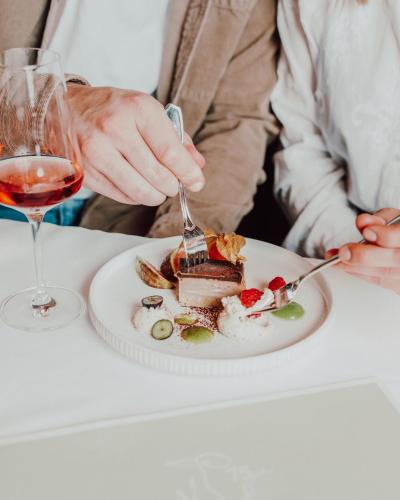 a person eating a dessert on a table with a glass of wine at Der Eisvogel - Wellness- & Genusshotel in Bad Gögging