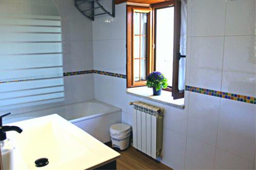 a white bathroom with a sink and a window at La Calleja Real in Liérganes