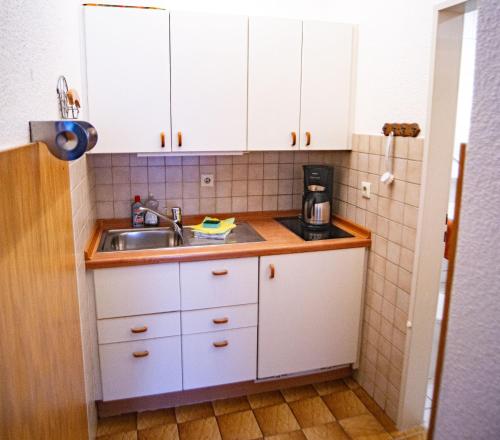 eine Küche mit weißen Schränken und einem Waschbecken in der Unterkunft Haus Ufen - In den Dünen 18c in Norderney