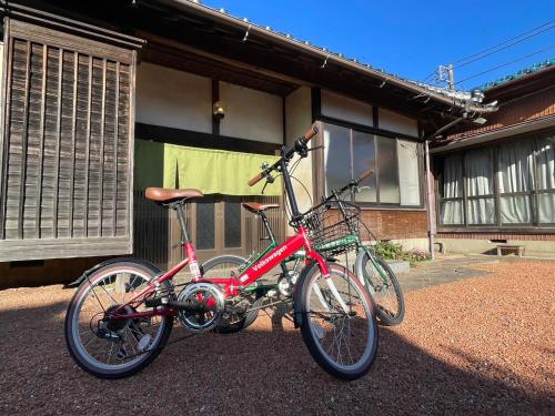uma bicicleta vermelha estacionada em frente a um edifício em 農家古民家ねこざえもん奥屋敷 Nekozaemon-Gest house em Nishiwada