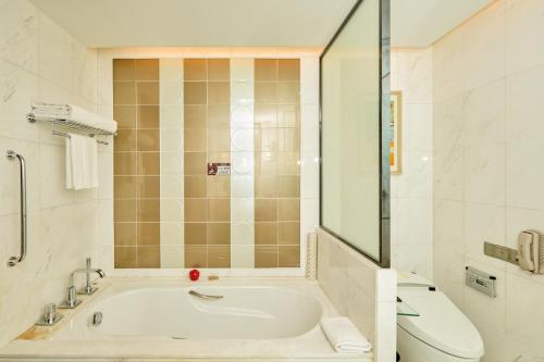 a white bathroom with a tub and a toilet at Soluxe Hotel Guangzhou - Overseas Buyers Registration Service&Canton Fair Free Shuttle Bus 15 Oct to 04 Nov in Guangzhou