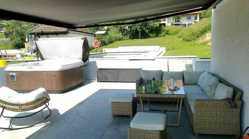 un patio con sofá, mesa y bañera en villa florian et vally, en Charvonnex
