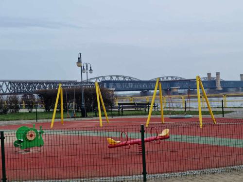 um parque infantil com baloiços amarelos num campo de ténis em Apartament Nad Wisłą u Ani em Tczew