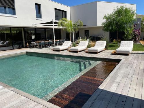 une piscine avec des chaises longues et une maison dans l'établissement Villa de luxe piscine jacuzzi, à Pérols