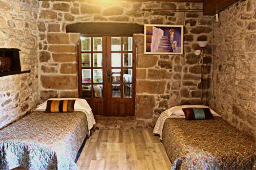 two beds in a room with a stone wall at La Calleja Real in Liérganes