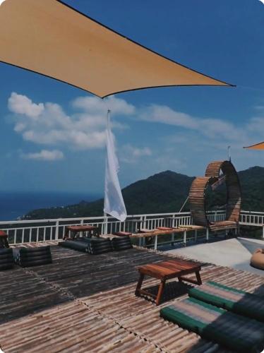 a deck with chairs and a table and an umbrella at Exotic Stay Koh Tao in Koh Tao