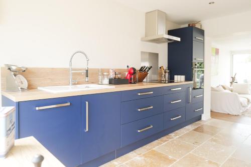 une cuisine avec des armoires bleues et un évier dans l'établissement Jolie maison rénovée proche centre ville Les Sables 9 personnes, à Les Sables-dʼOlonne