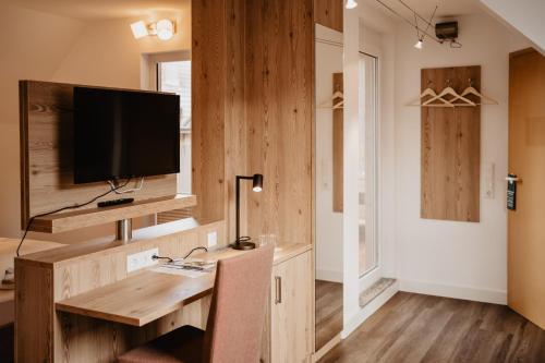 een kamer met een houten bureau en een televisie. bij Hotel Garni Stube in Königschaffhausen