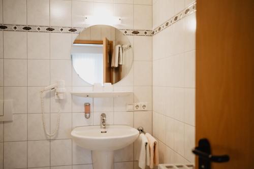 a white bathroom with a sink and a mirror at Hotel Garni Stube in Königschaffhausen