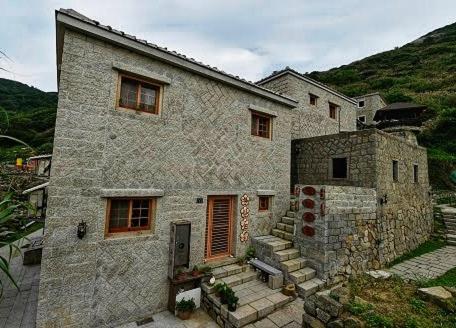 Une grande maison en pierre avec des escaliers se trouve juste devant. dans l'établissement 芹壁梅好石屋 Mayhao Stone House, à Beigan