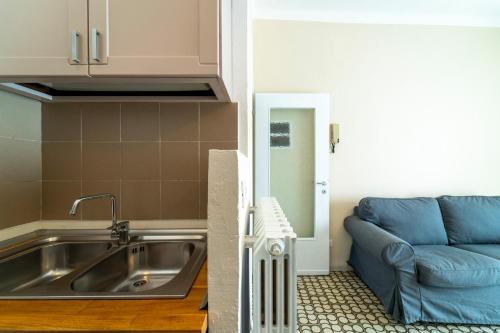 eine Küche mit einem Waschbecken und einem blauen Sofa in der Unterkunft Lotus Apartment by Wonderful Italy in Bellagio