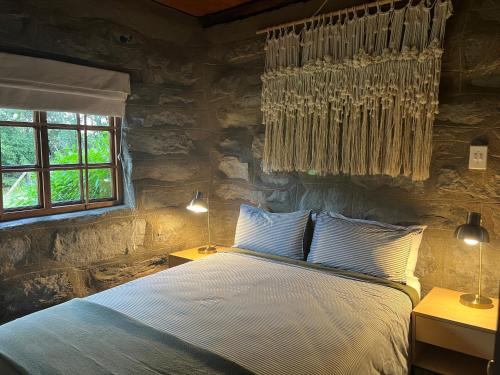 1 dormitorio con cama y pared de piedra en Wyford Farm, en Van Reenen