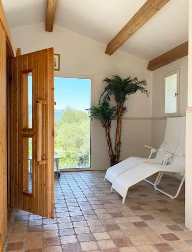 Cette chambre comprend un lit, une chaise et une fenêtre. dans l'établissement Maison avec piscine sur les hauteurs de Valbonne, à Valbonne