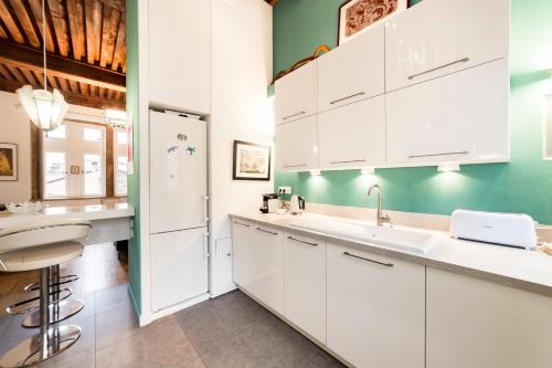 - une cuisine avec des placards blancs et un mur vert dans l'établissement Grand duplex au cœur du Vieux Lyon, à Lyon