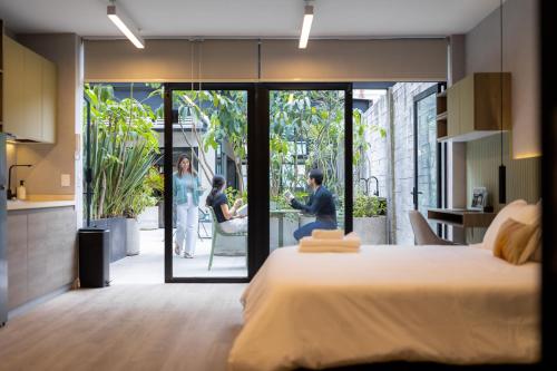 a bedroom with a large bed and people standing outside at Outsite Mexico City Roma Sur - Work, Connect, Explore in Mexico City